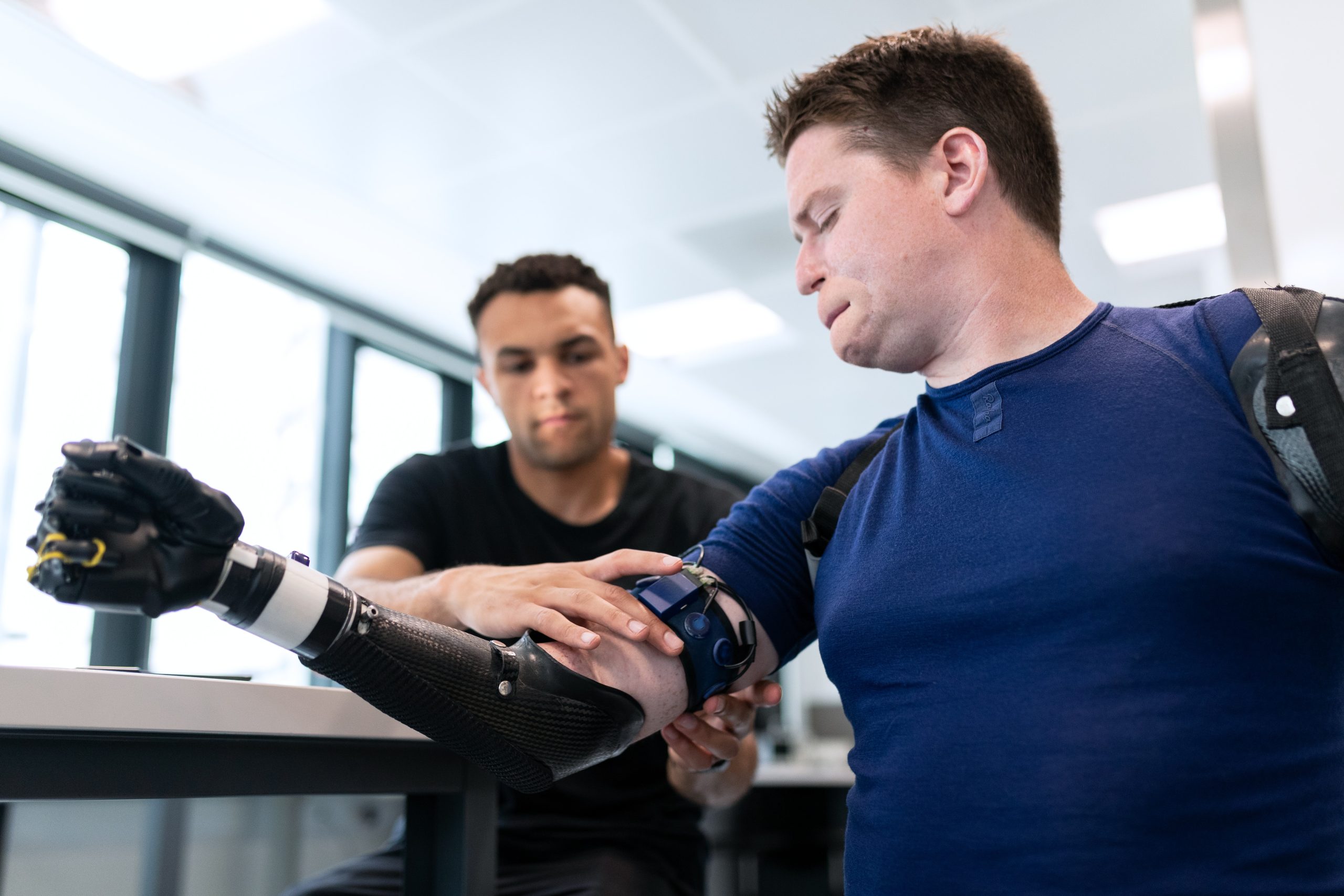 A technician fits a man with a prosthetic arm