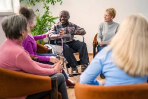 A group of diverse older people chatting with a counsellor during a therapy session in a residential care home